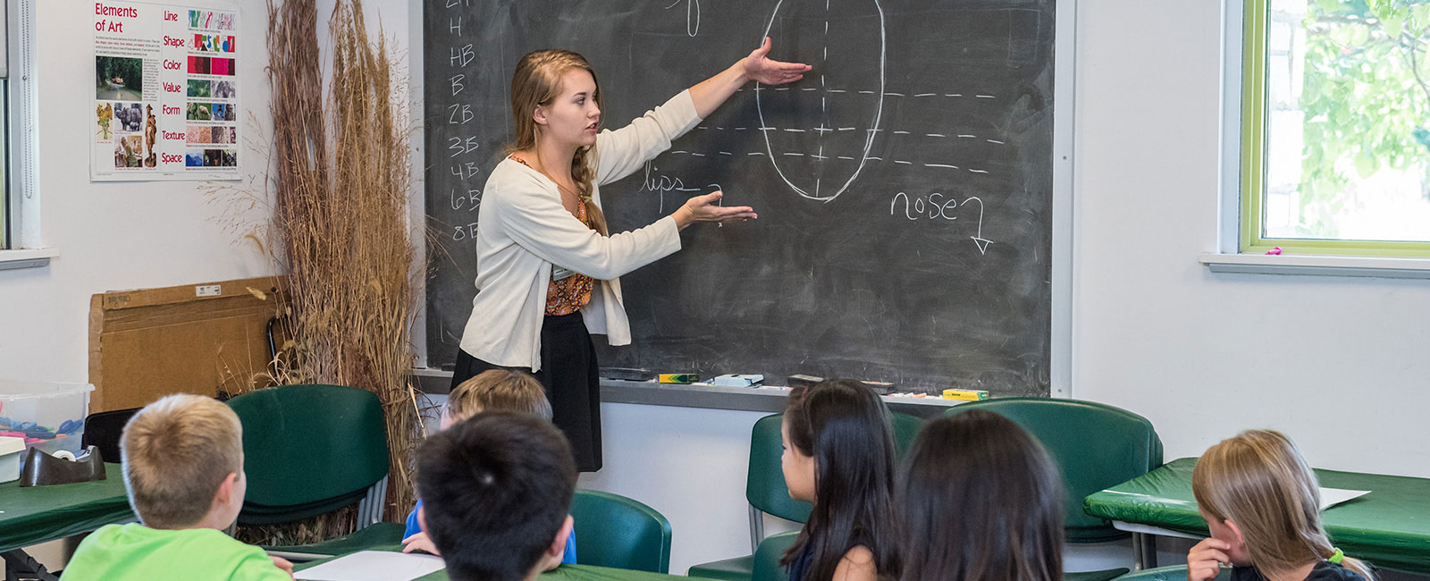 A teacher instructing children at a blackboard