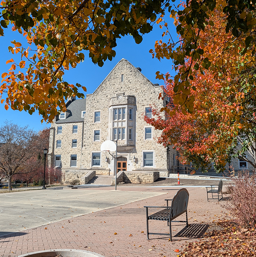An exterior shot shows a limestone college residence hall in the autumn.