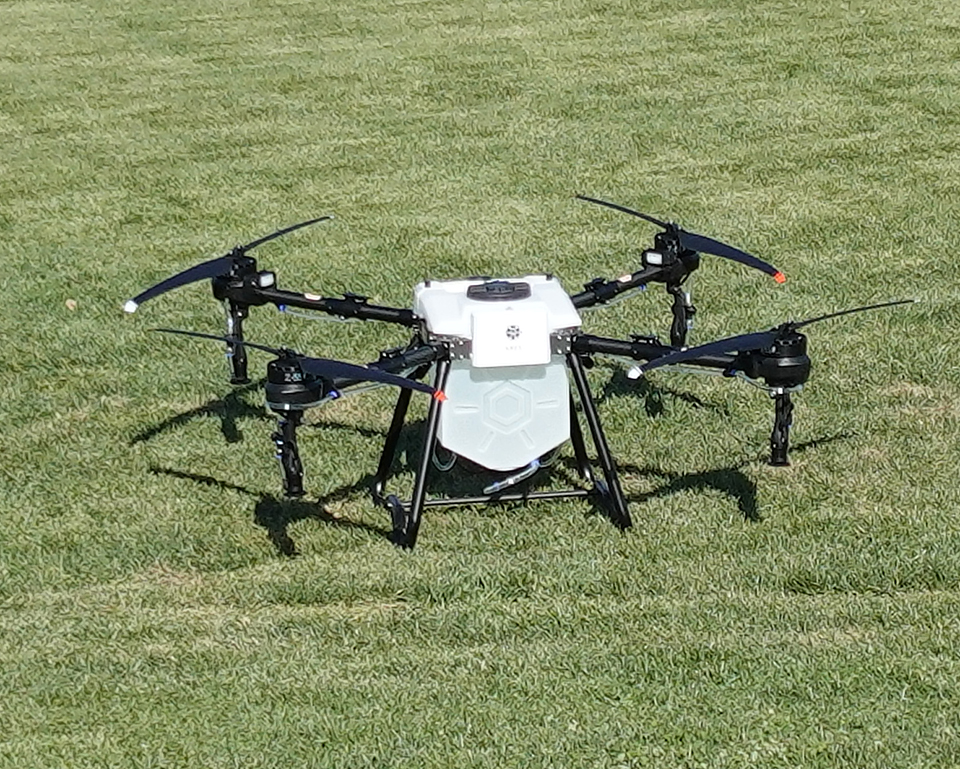 A large drone sits on a lawn, preparing to take off.