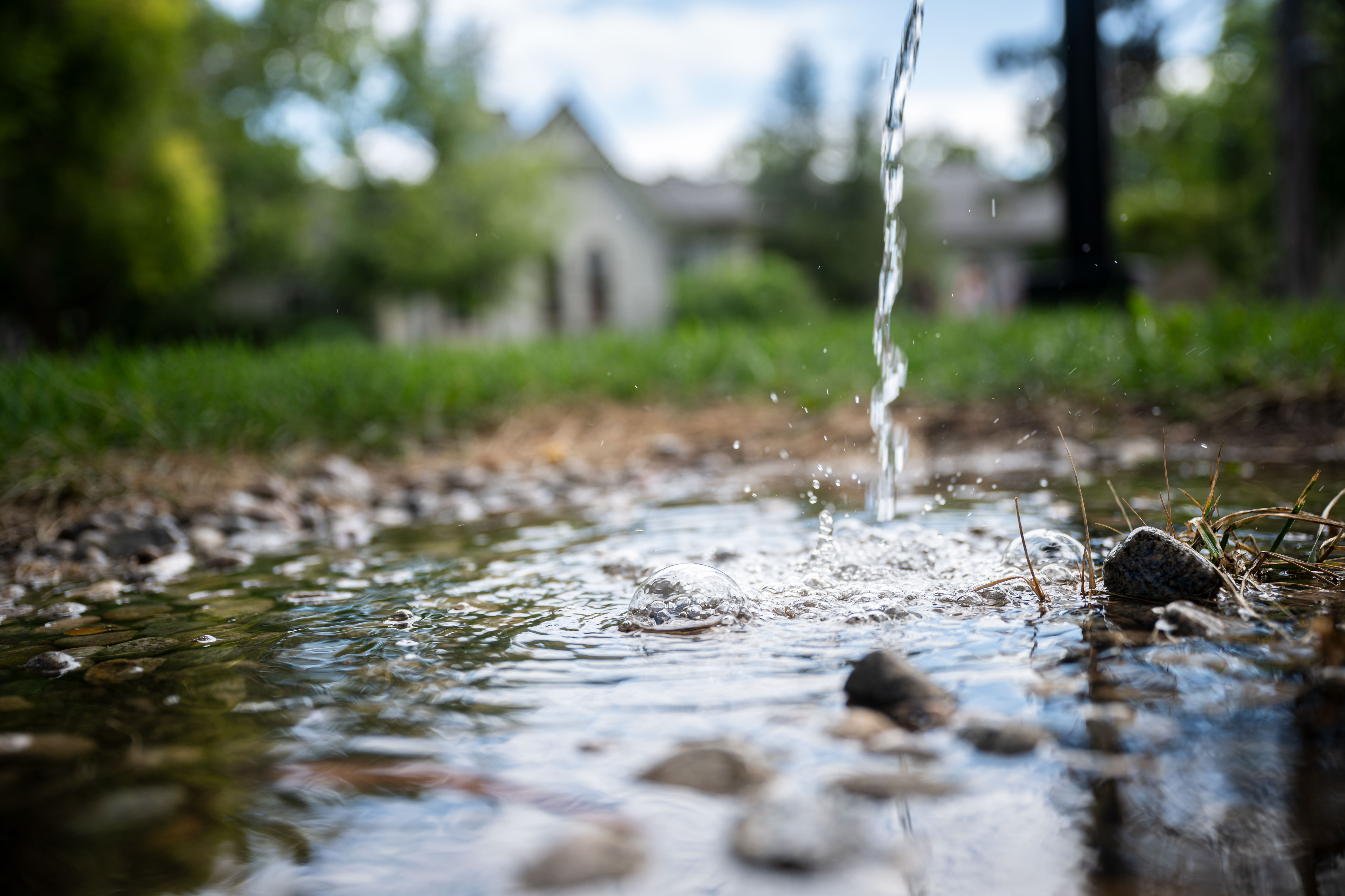 Water runs from a spout and splashes on the ground. 