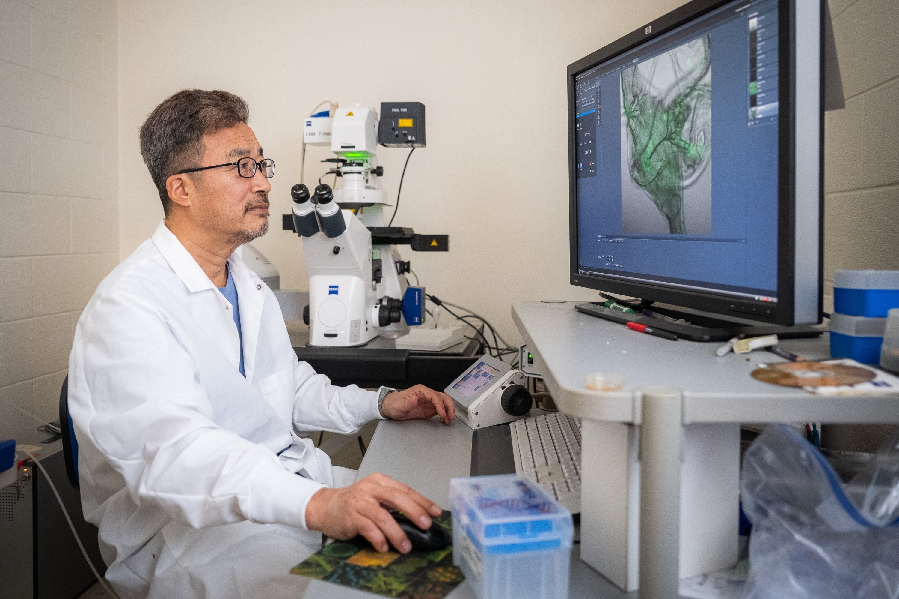 Yoonseong Park, wearing a white labcoat, looks at research results on his computer.