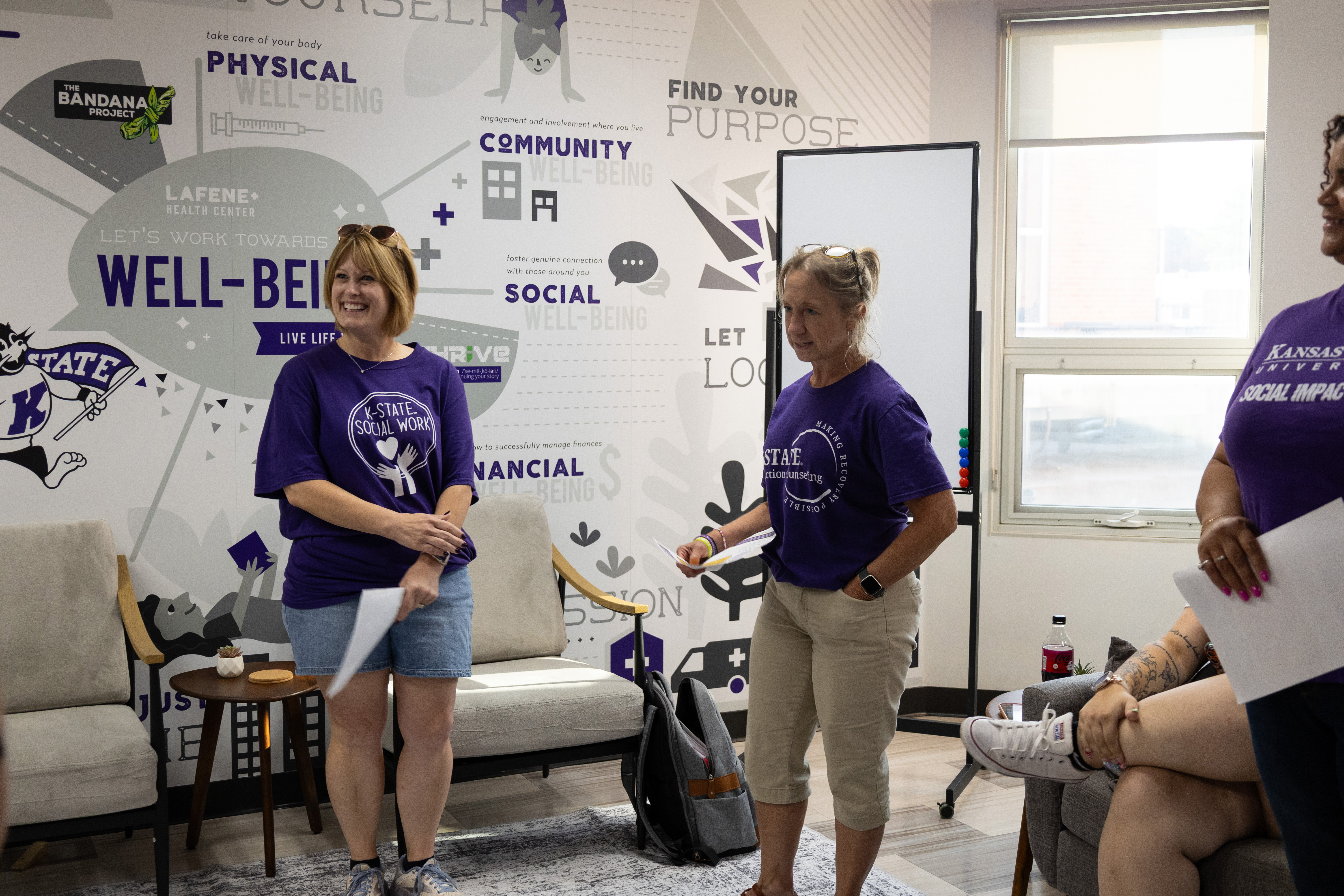 Two female university staff members stand together and speak during a group discussion.