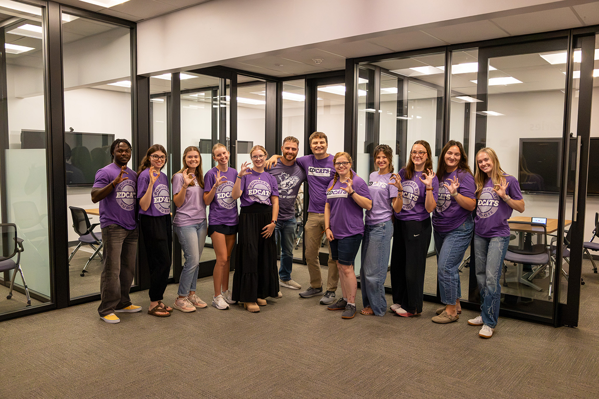 A group of college students pose for a portrait in a college collaboration space.