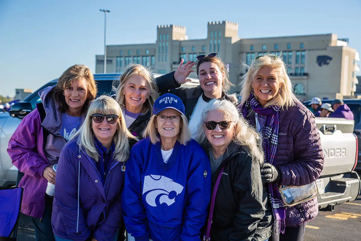 A group of K-STate alumni posing for a photo outside of Bill Snyder Stadium.