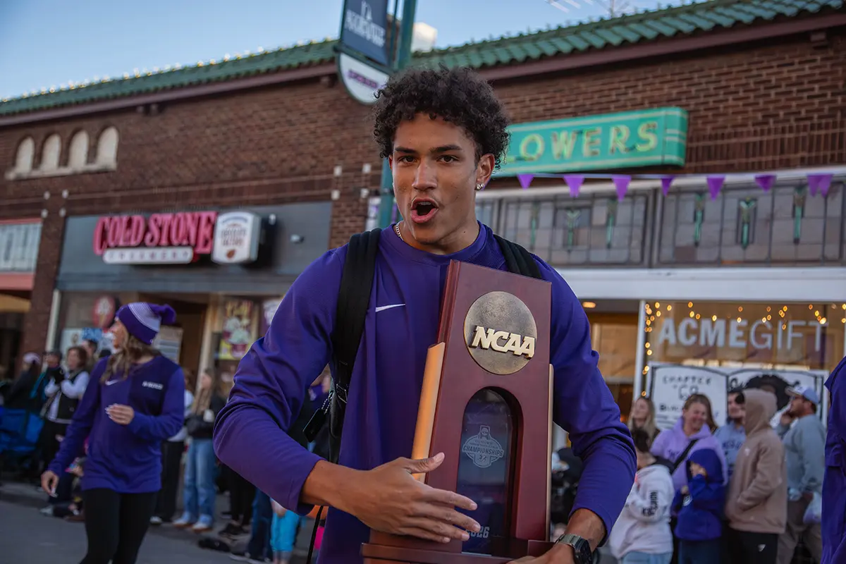 Track & Field athlete holding the NCAA trophy.