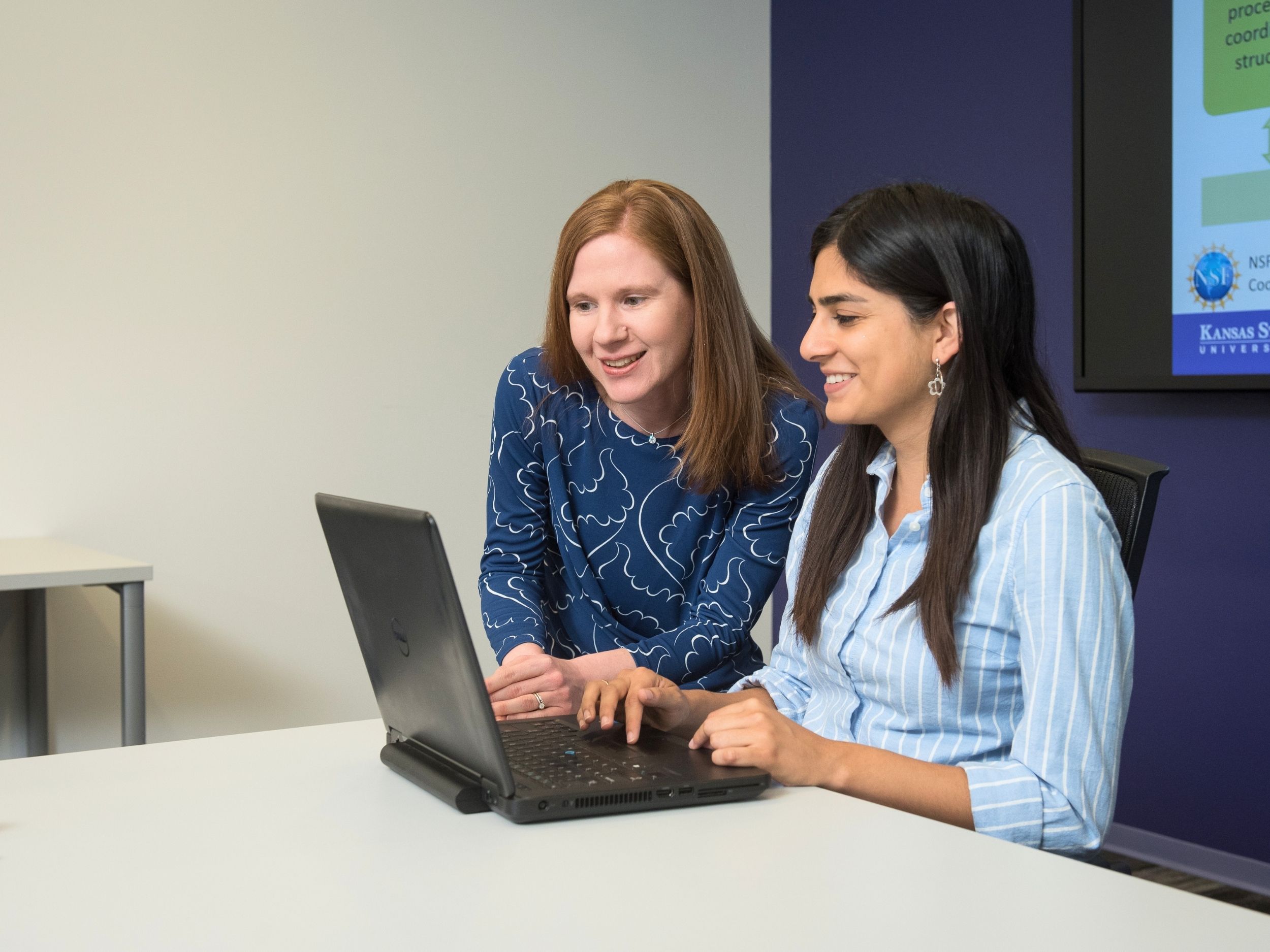 Jessica Heier Stamm sits with a student, overlookng a computer
