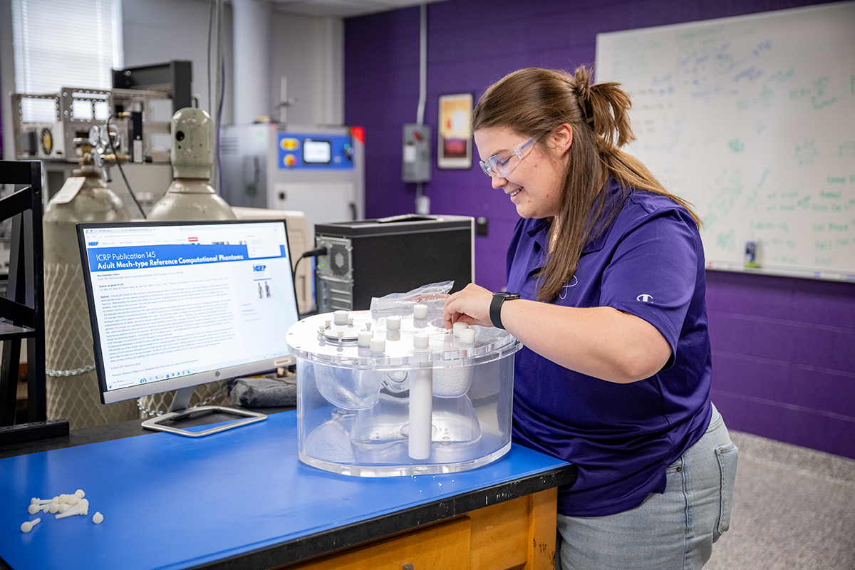 A student in safety glasses works on a project as part of their nuclear engineering education.